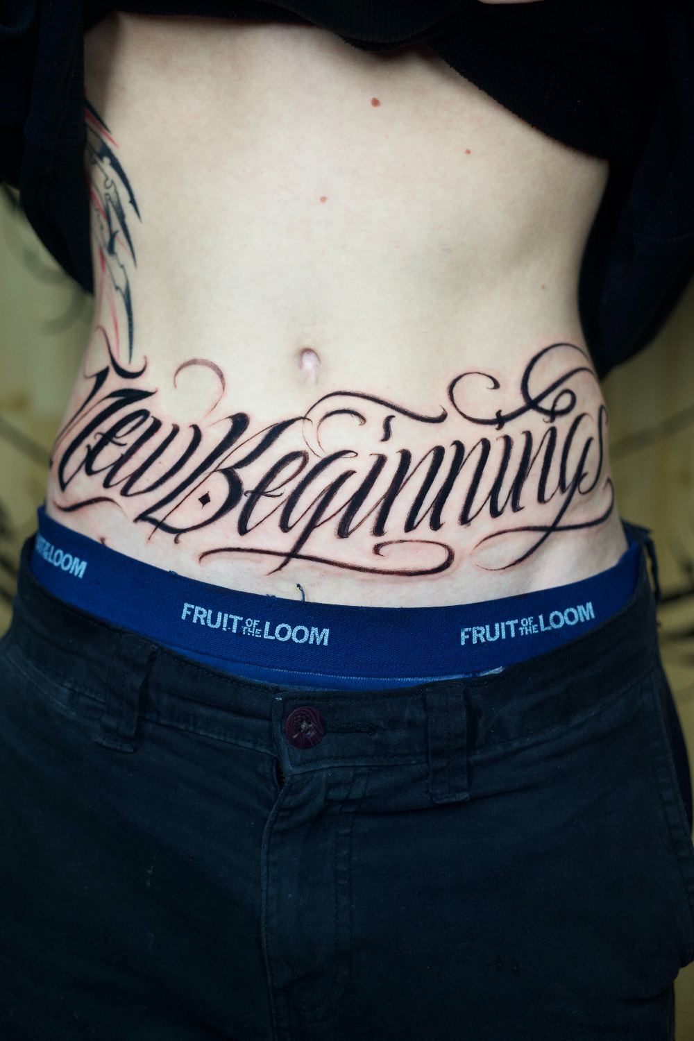 script lettering stomach tattoo reading New Beginnings by Antwan Rodriguez, West Palm Beach FL